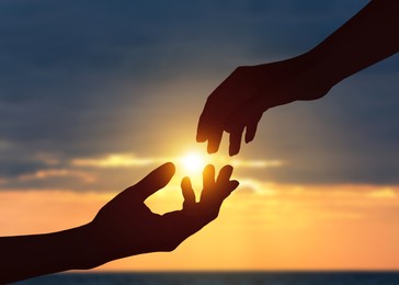 Image of Hope. Women holding hands against sky with clouds and sun, closeup
