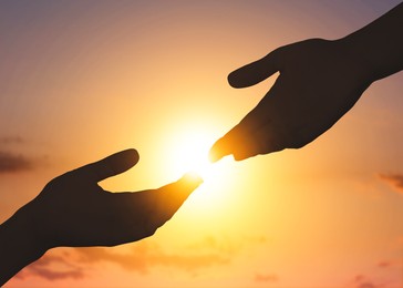 Image of Hope. Women holding hands against sky with bright sun, closeup