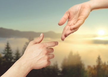 Image of Hope. Woman and man holding hands against sky with clouds and sun in mountains, closeup