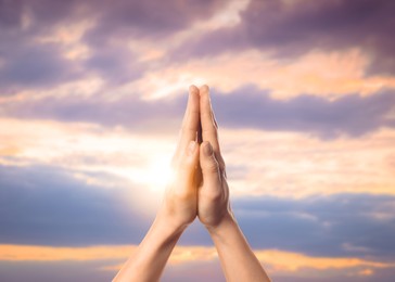 Image of Hope. Woman praying and holding hands against sky with clouds and sun, closeup
