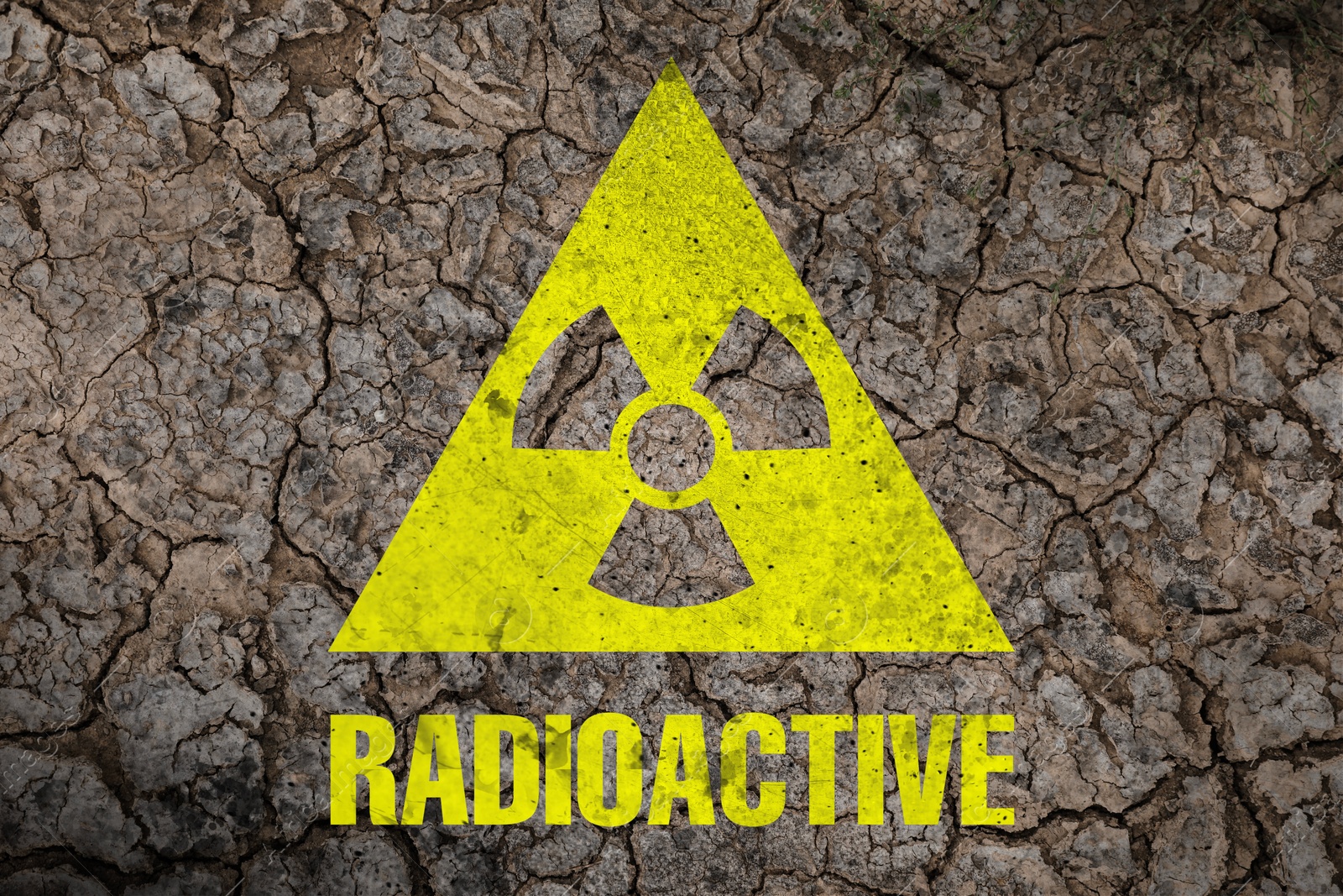 Image of Yellow radioactive sign on cracked dry earth, top view. Radiological pollution