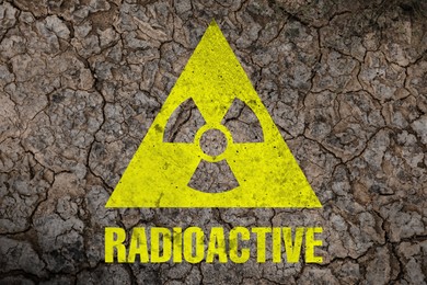 Image of Yellow radioactive sign on cracked dry earth, top view. Radiological pollution