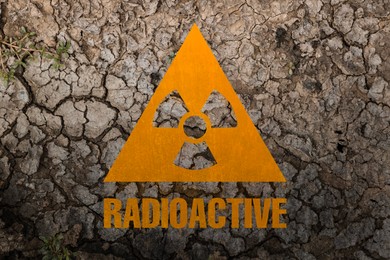 Image of Orange radioactive sign on cracked dry earth, top view. Radiological pollution