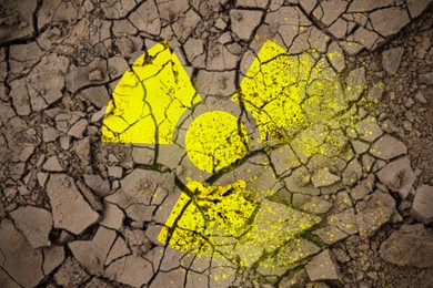 Image of Yellow radioactive sign on cracked dry earth, top view. Radiological pollution