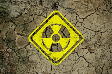 Image of Yellow radioactive sign on cracked dry earth, top view. Radiological pollution