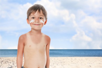 Image of Little boy with sunburned skin on beach. Soothing cream on his cheeks