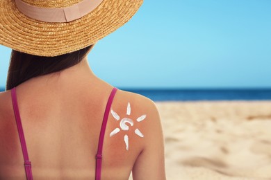 Image of Woman with sunburned skin on beach, back view. Soothing cream in shape of sun on her body