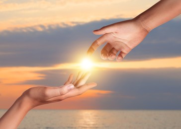 Image of Hope. Women holding hands against sky with clouds and sun, closeup