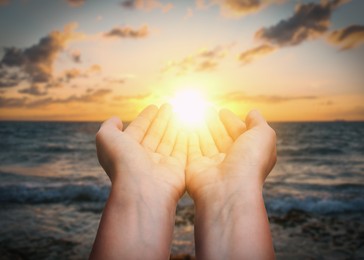 Image of Hope. Woman holding hands against sky with clouds and sun, closeup