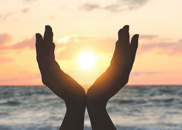 Image of Hope. Woman holding hands against sky with clouds and sun, closeup