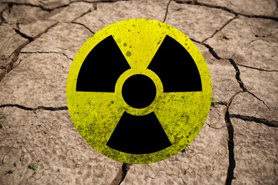 Image of Yellow radioactive sign on cracked dry earth, closeup. Radiological pollution