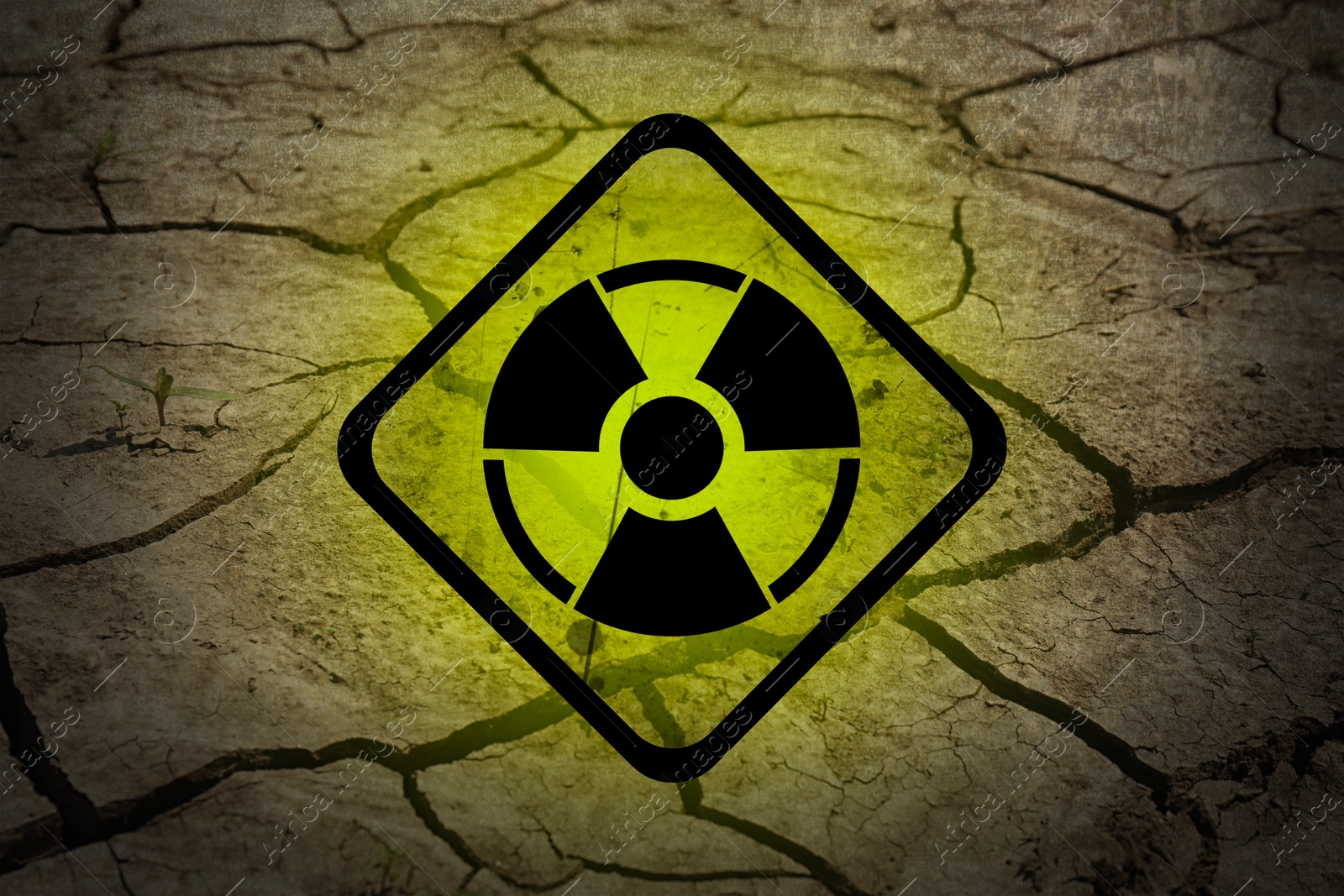 Image of Yellow radioactive sign on cracked dry earth, closeup. Radiological pollution