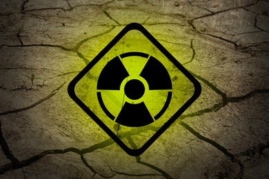Image of Yellow radioactive sign on cracked dry earth, closeup. Radiological pollution