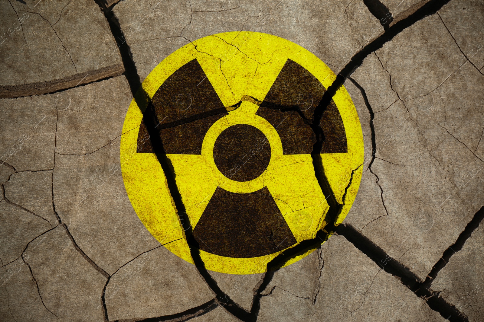 Image of Yellow radioactive sign on cracked dry earth, top view. Radiological pollution
