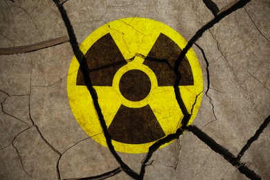 Image of Yellow radioactive sign on cracked dry earth, top view. Radiological pollution