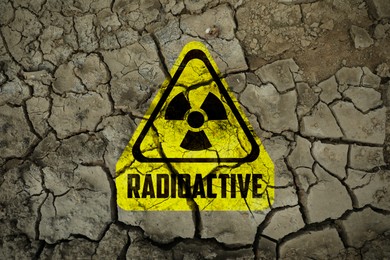 Image of Yellow radioactive sign on cracked dry earth, top view. Radiological pollution