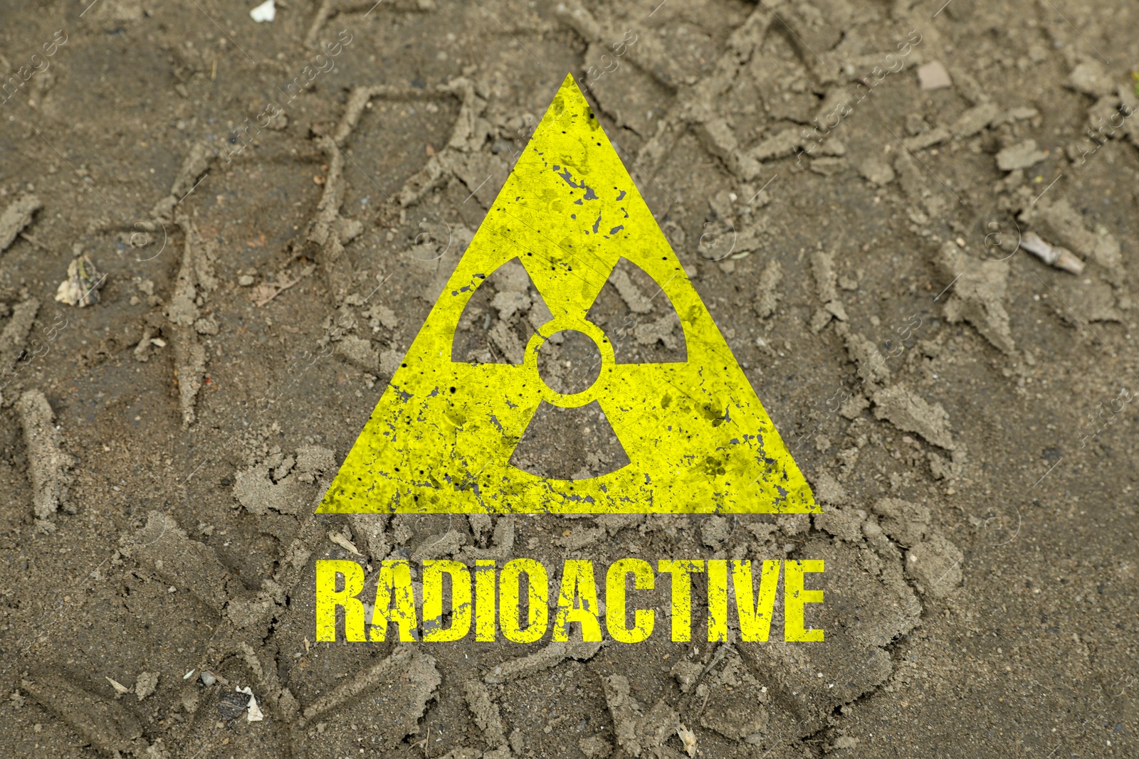 Image of Yellow radioactive sign on ground with tire tracks, closeup. Radiological pollution
