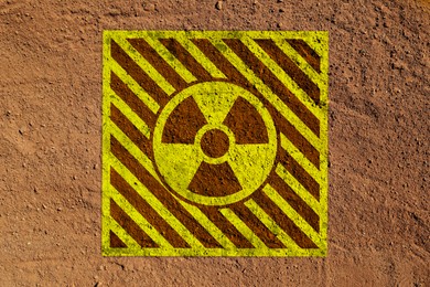 Image of Yellow radioactive sign on brown ground, top view. Radiological pollution