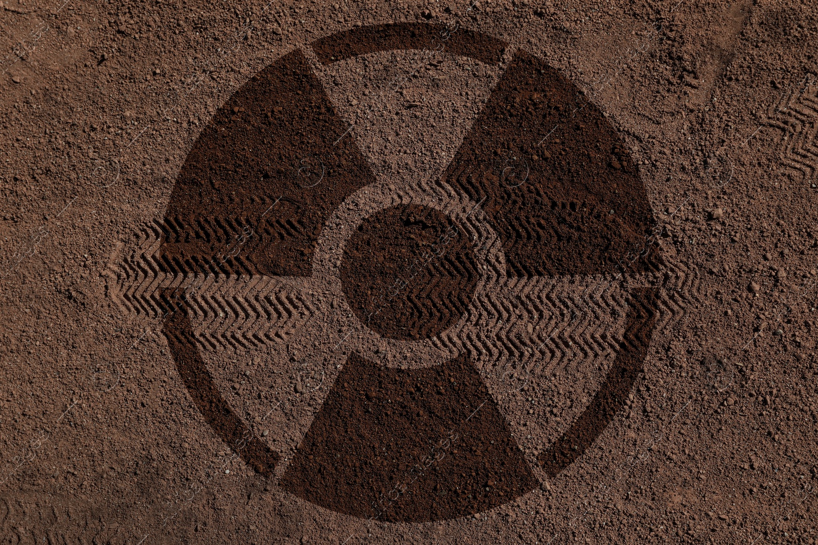 Image of Radioactive sign on brown ground with shoes tracks, top view. Radiological pollution