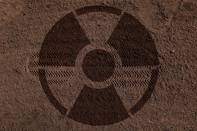 Image of Radioactive sign on brown ground with shoes tracks, top view. Radiological pollution