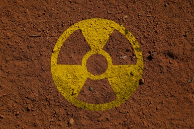 Image of Radioactive sign on brown ground, top view. Radiological pollution