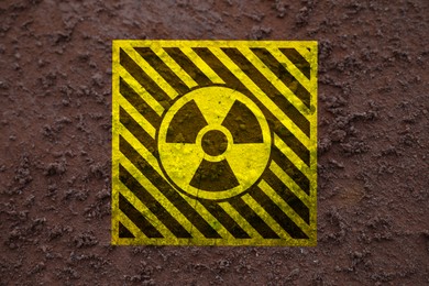 Image of Yellow radioactive sign on brown ground, top view. Radiological pollution