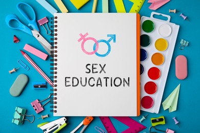 Image of Sex Education inscription, female and male gender symbols in notebook and stationery on blue background, top view