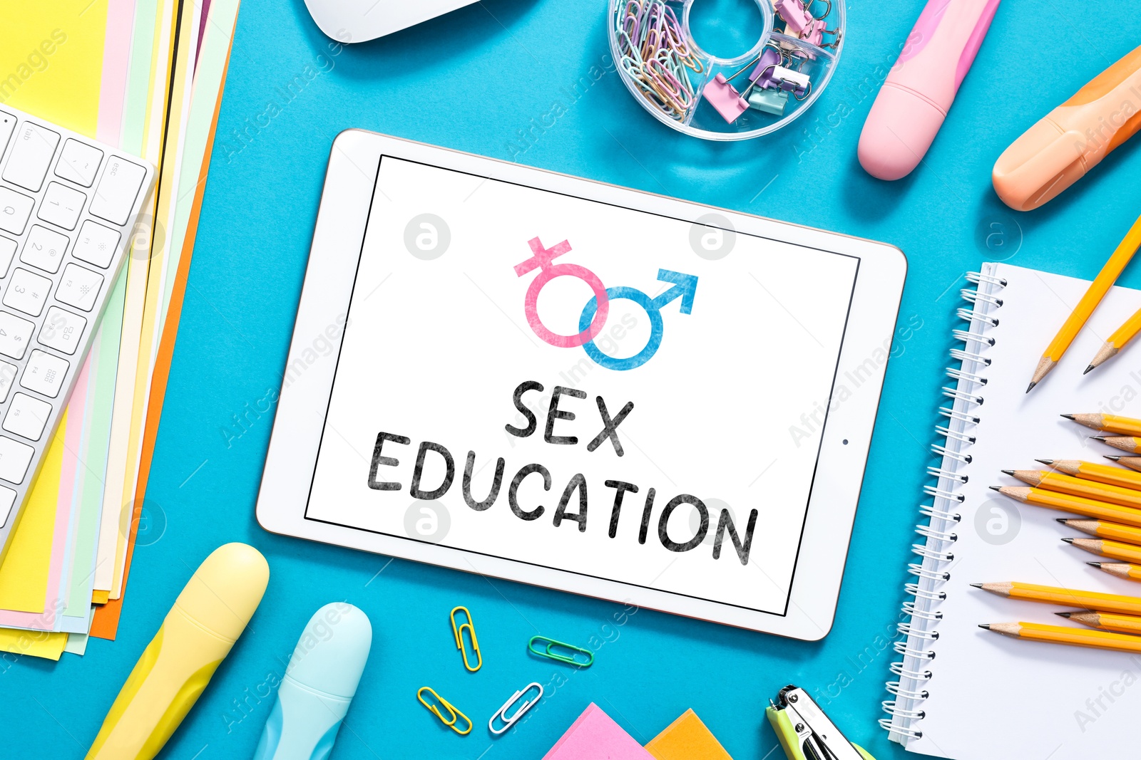 Sex education. Tablet computer and stationery on blue background, flat lay Image of Sex education. Tablet computer and stationery on blue background, flat lay