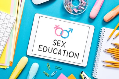 Image of Sex education. Tablet computer and stationery on blue background, flat lay