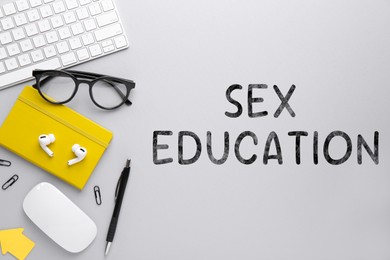 Image of Sex Education inscription, glasses, computer keyboard and stationery on white background, top view