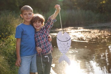 Photo of Children with paper fish in nature on sunny day