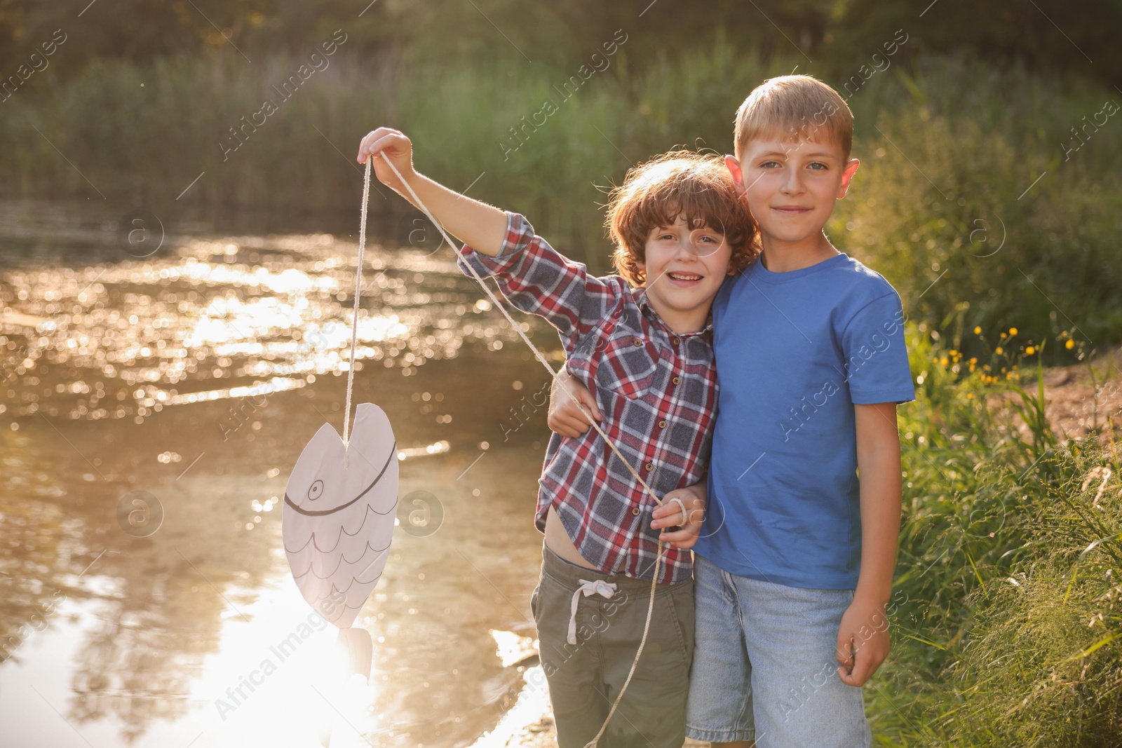 Children with paper fish in nature on sunny day Photo of Children with paper fish in nature on sunny day