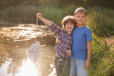 Photo of Children with paper fish in nature on sunny day