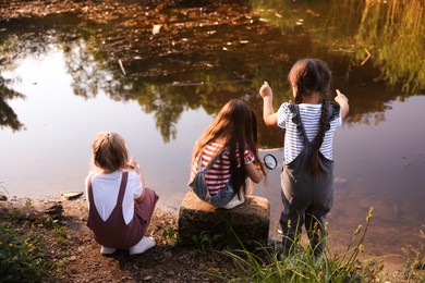 Photo of Children playing by lake in nature, back view
