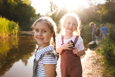 Photo of Children spending time in nature. Cute little girls by lake, selective focus