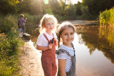 Photo of Children spending time in nature. Cute little girls by lake, selective focus
