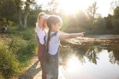 Photo of Cute little girls spending time by lake in nature