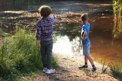 Photo of Children spending time by lake in nature, back view