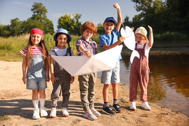 Photo of Children with paper boat and fish by lake in nature