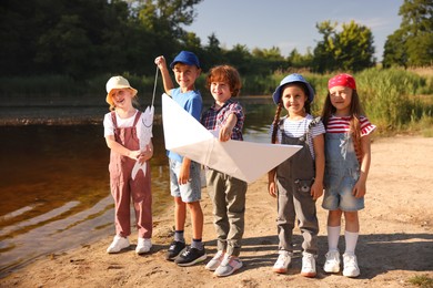 Photo of Children with paper boat and fish by lake in nature
