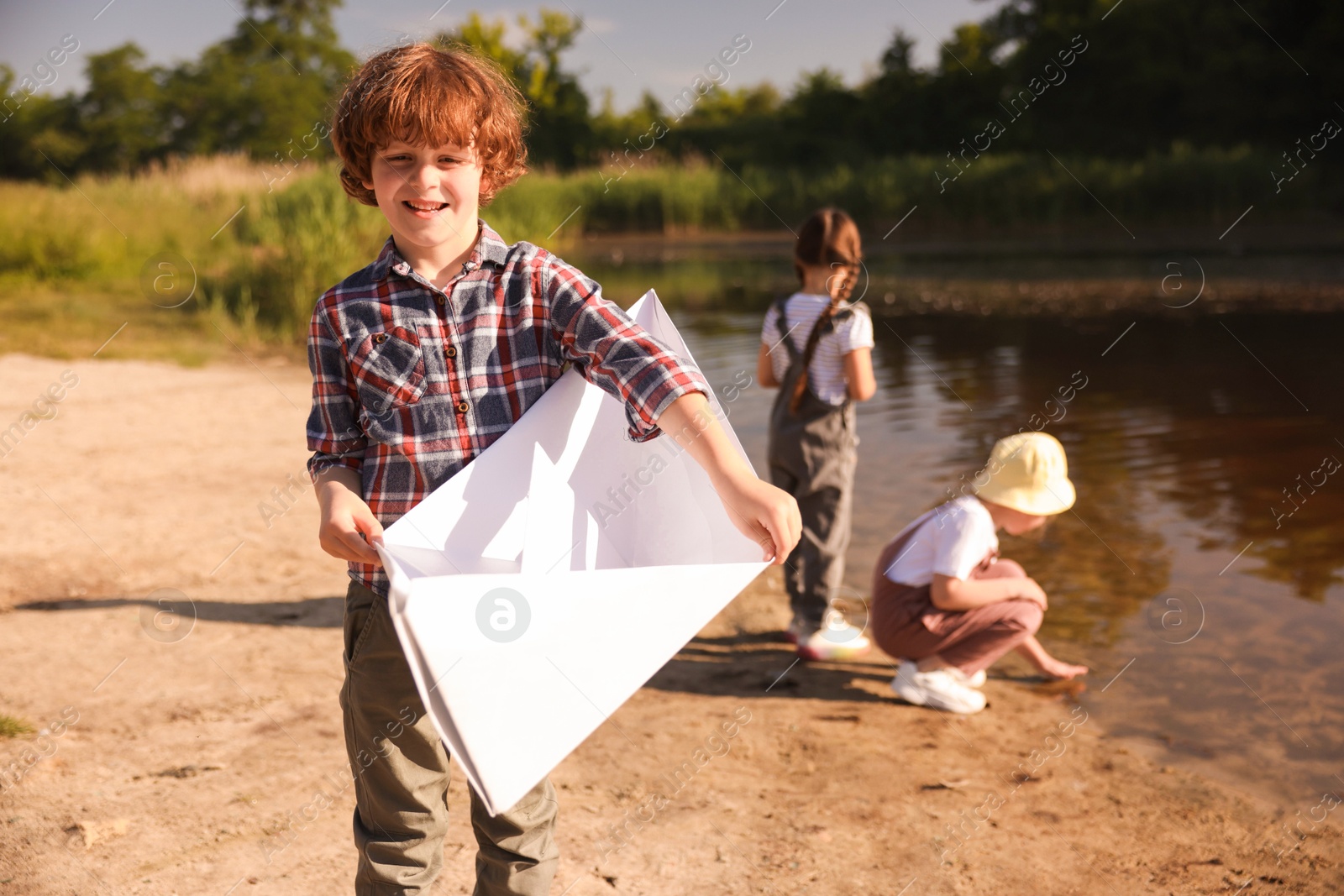 Children in nature, selective focus. Cute little boy with paper boat by lake Photo of Children in nature, selective focus. Cute little boy with paper boat by lake