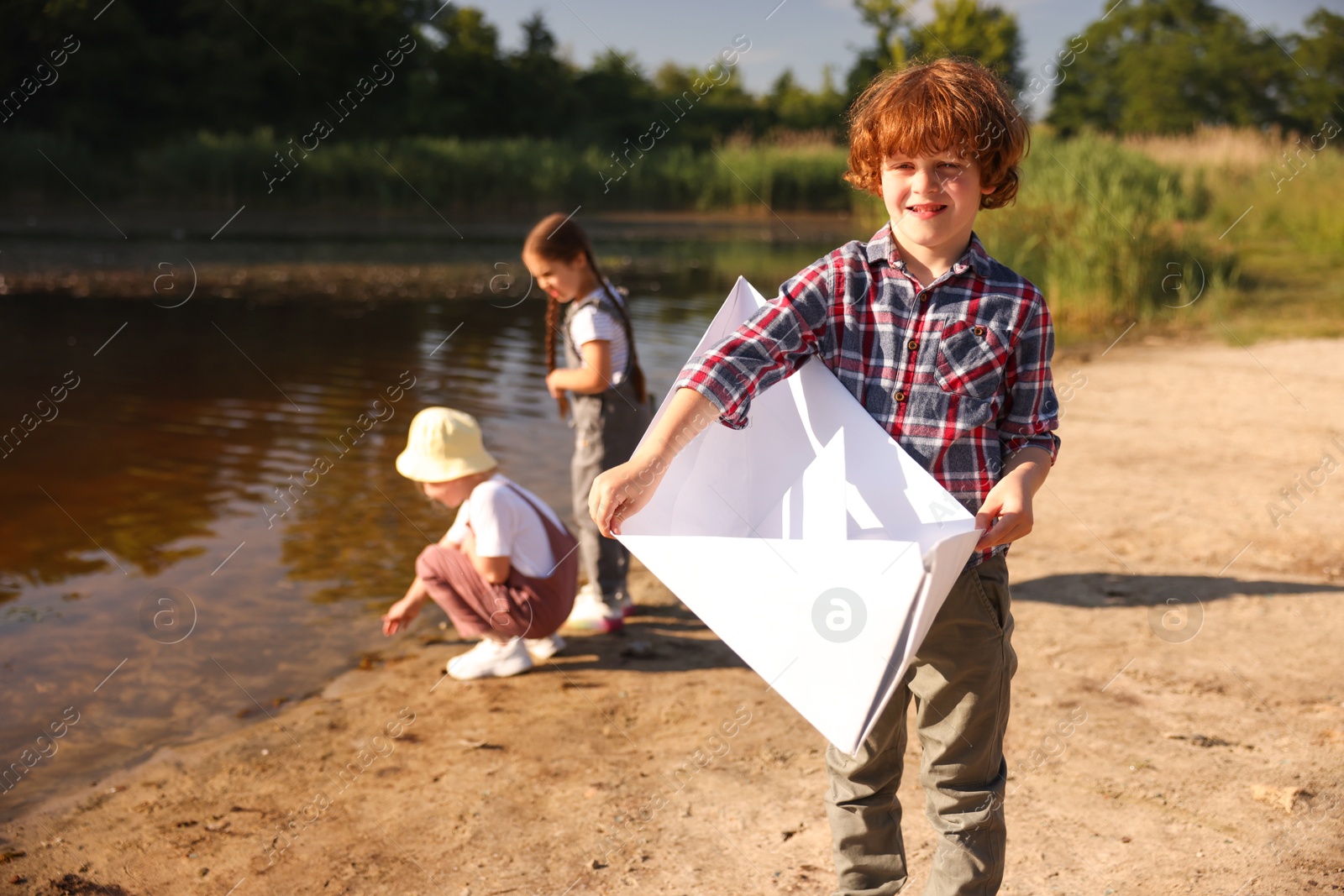 Children in nature, selective focus. Cute little boy with paper boat by lake Photo of Children in nature, selective focus. Cute little boy with paper boat by lake