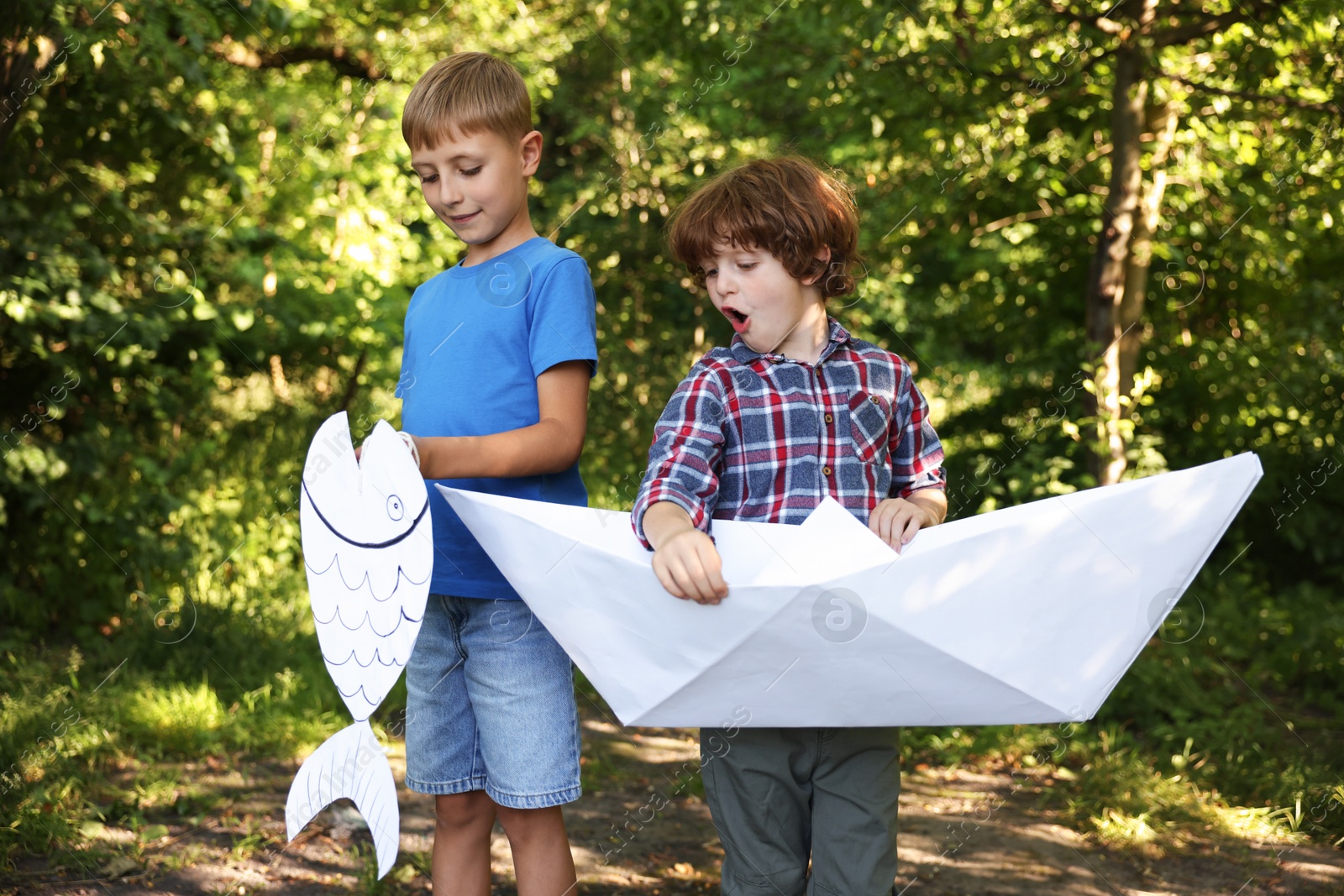 Children with paper boat and fish in nature Photo of Children with paper boat and fish in nature