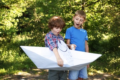 Photo of Children with paper boat and fish in nature