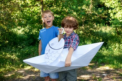 Photo of Children with paper boat and fish in nature