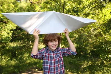 Photo of Cute little boy with paper boat in nature