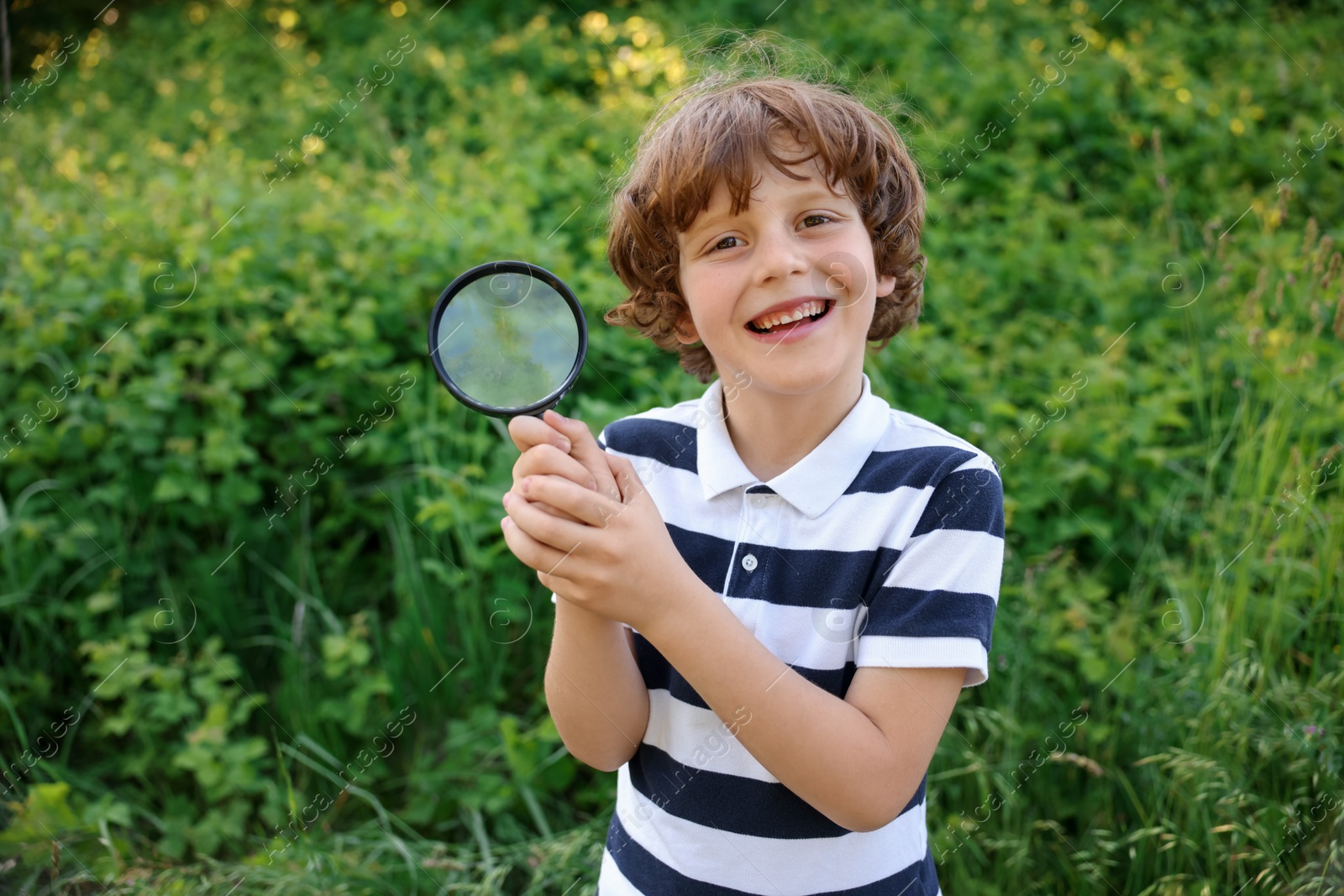Cute little boy with magnifying glass in nature Photo of Cute little boy with magnifying glass in nature
