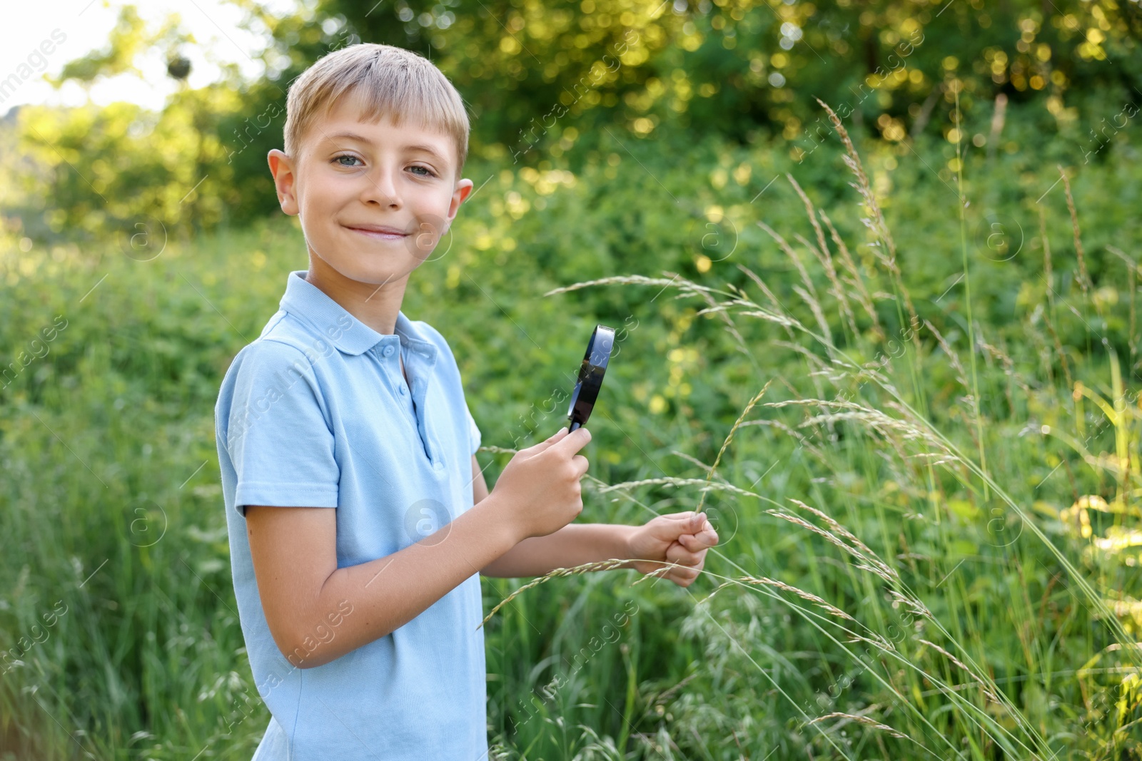 Cute little boy with magnifying glass in nature. Space for text Photo of Cute little boy with magnifying glass in nature. Space for text
