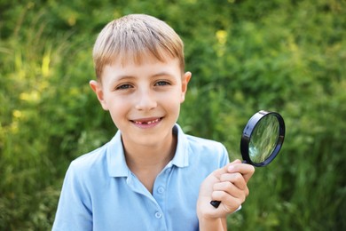 Photo of Cute little boy with magnifying glass in nature