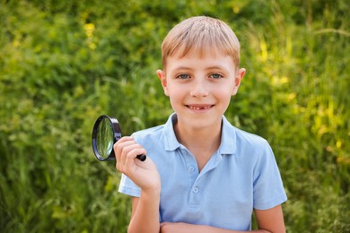 Photo of Cute little boy with magnifying glass in nature